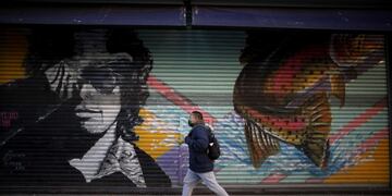 Un hombre camina por la calle con negocios cerrados por la pandemia. (AP Photo/Natacha Pisarenko)