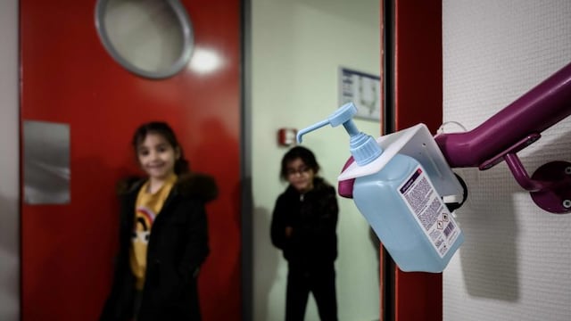 Los niños se desinfectan las manos con alcohol en gel antes de entrar al aula. (Foto: AFP)