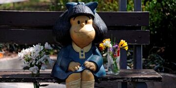 TOPSHOT - Flowers are seen by a statue depicting Mafalda, a comic strip character created by Argentinian cartoonist Joaquin Salvador Lavado, known as Quino, in Mendoza, Argentina, on September 30, 2020, on the day of his death\u002E - Quino passed away Wednesday at 88, his editor confirmed\u002E (Photo by Andres LARROVERE / AFP)