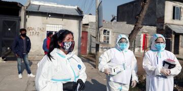 A healthcare worker wearing a face mask depicting Eva Peron, wife of late Argentina's President Juan Domingo Peron, also known as 'Evita', stands outside a house before asking residents for coronavirus disease (COVID-19) symptoms, as part of the 'detectar' plan, in Villa Fiorito, on the outskirts of Buenos Aires, Argentina August 3, 2020\u002E REUTERS/Agustin Marcarian