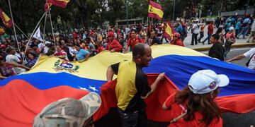 Supporters of President Nicolas Maduro hold a Venezuelan national flag during a demonstration in Caracas on October 18, 2016.nVenezuela's Supreme Court has raised another obstacle to an opposition drive for a referendum on recalling leftist President Nicolas Maduro, who is blamed for a deepening economic and political crisis. / AFP PHOTO / JUAN BARRETO