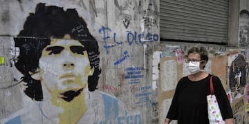 Una mujer camina junto a un mural de Diego Maradona (Foto: JUAN MABROMATA / AFP)