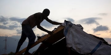 In this Dec. 2, 2016 photo, a man breaks downs his shelter in the Delmas tent camp set up nearly seven years ago for people displaced by the 2010 earthquake, in Port-au-Prince, Haiti. The man has agreed to resettle and move into a one-year rental provided