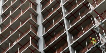 A worker looks out from the construction site of the Sailmakers building, being constructed by Greystar Europe Holdings Ltd\u002E, near the Canary Wharf financial, business and shopping district in London, U\u002EK\u002E, on Tuesday, July 25, 2017\u002E U\u002EK\u002E house prices are \