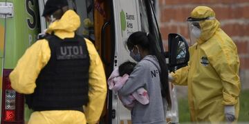 A woman carrying a baby with symptoms of the new coronavirus gets in an ambulance at the Villa Azul shantytown after the provincial government detected at least 53 people infected with COVID-19 and decided to isolate the entire neighborhood, in Quilmes, Buenos Aires province, Argentina, on May 25, 2020\u002E (Photo by JUAN MABROMATA / AFP)