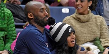 FILE - In this March 2, 2019, file photo, Kobe Bryant and his daughter Gianna watch the first half of an NCAA college basketball game between Connecticut and Houston in Storrs, Conn\u002E Autopsy reports released Friday, May 15, 2020, show that the pilot who flew Bryant show he did not have drugs or alcohol in his system when the helicopter crashed in Southern California in January, killing all nine aboard\u002E The causes of death for Bryant, his 13-year-old daughter Gianna, pilot Ara Zobayan and the others have been ruled blunt force trauma\u002E Federal authorities are still investigating the Jan\u002E 26 incident where the chopper crashed into the Calabasas hillsides\u002E (AP Photo/Jessica Hill, File)