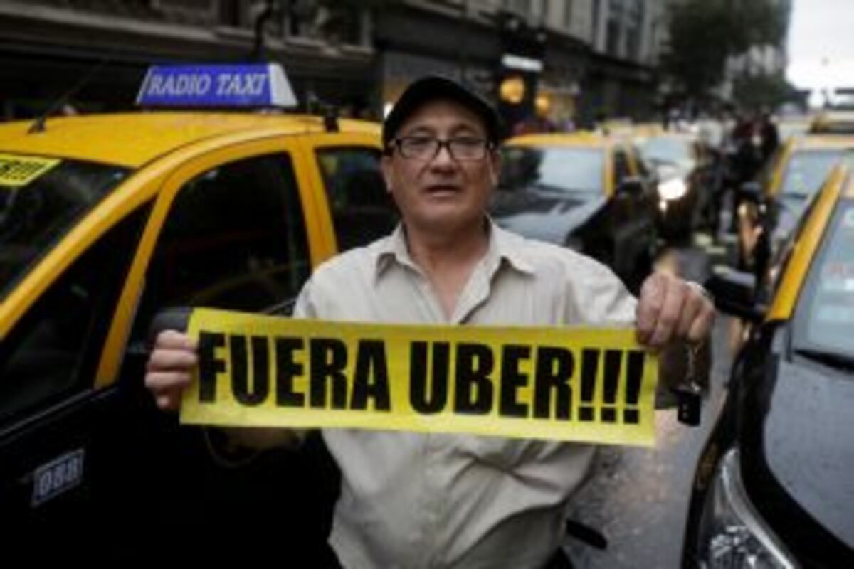 A taxi driver holds a sign that reads in Spanish