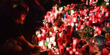 People lay flowers, candles and other items at a makeshift memorial set up on the Las Ramblas boulevard in Barcelona as they pay tribute to the victims of the Barcelona attack, a day after a van ploughed into the crowd, killing 14 persons and injuring over 100 on August 18, 2017\u002E \nDrivers have ploughed on August 17, 2017 into pedestrians in two quick-succession, separate attacks in Barcelona and another popular Spanish seaside city, leaving 14 people dead and injuring more than 100 others\u002E Some eight hours later in Cambrils, a city 120 kilometres south of Barcelona, an Audi A3 car rammed into pedestrians, injuring six civilians -- one of them critical -- and a police officer, authorities said\u002E / AFP PHOTO / Pascal GUYOT