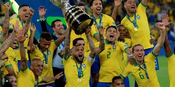 Brazil's Dani Alves (C) and teammates celebrates with the trophy after winning the Copa America after defeating Peru in the final match of the football tournament at Maracana Stadium in Rio de Janeiro, Brazil, on July 7, 2019\u002E (Photo by Juan MABROMATA / AFP)