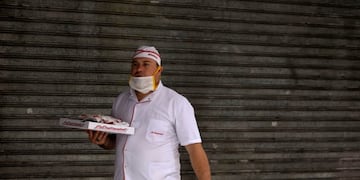 A delivery man with a pizza walks past a closed store in Buenos Aires, Argentina, Wednesday, April 1, 2020, during a government ordered lock down to contain the spread of the new coronavirus\u002E COVID-19 disease causes mild or moderate symptoms for most people, but for some, especially older adults and people with existing health problems, it can cause more severe illness or death\u002E (AP Photo/Natacha Pisarenko)