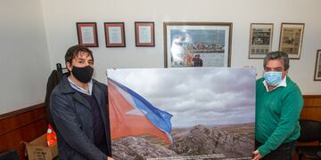 Omar Becerra, recibió al periodista Mariano López quien hizo entrega de dos cuadros con la imagen de la bandera de la Provincia flameando en el monte Tumbledown.