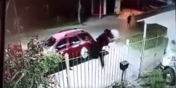 El momento preciso en que el joven trepa la reja escapando de los asaltantes. Foto captura de pantalla @CtralDeNoticias