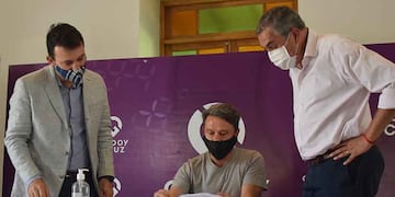 El intendente de Godoy Cruz García Zalazar y el ministro Vaquié observan la firma de uno de los adherentes al programa Mendoza Activa. Gentileza Municipalidad de Godoy Cruz