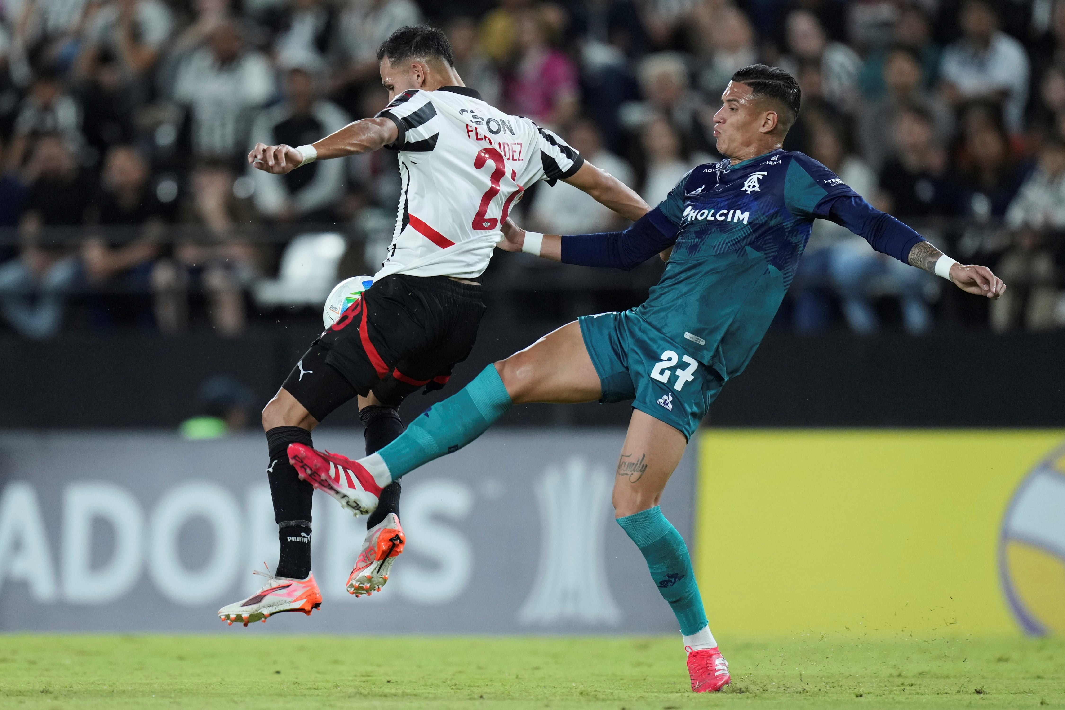 Juan Camilo Portilla en acción ante Marcelo Fernández, en la visita de Talleres a Libertad por la Copa Libertadores. (AP)