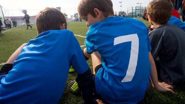 Niños en una cancha de fútbol sentados en el césped