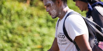 Un migrante con protector solar en el rostro camina sobre la carretera en Escuintla, en el sur de México, en su odisea hacia la frontera norte del país y con destino a Estados Unidos, el jueves 7 de noviembre de 2024. (AP Foto/Moisés Castillo)
