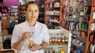 Guadalupe Ñañez en su farmacia y con su repelente de elaboración propia.