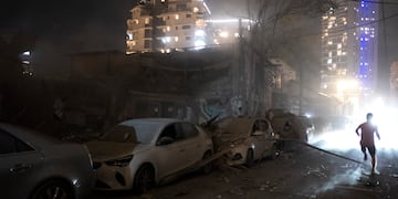 Gente caminando junto a los daños causados por un cohete lanzado desde la Franja de Gaza en Tel Aviv, Israel, el sábado 7 de octubre de 2023.