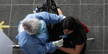 Una persona del personal sanitario realiza una prueba de coronavirus a una viajera en una terminal de transporte en Buenos Aires. (Foto: EFE/ Juan Ignacio Roncoroni)