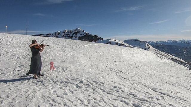 Tania Rubiolo tocando el violín en el cerro Teta para concientizar sobre el cáncer de mama.
