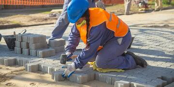 Dos mujeres de Pérez trabajan colocando adoquines en las calles en barrio 78 Viviendas (La Capital)