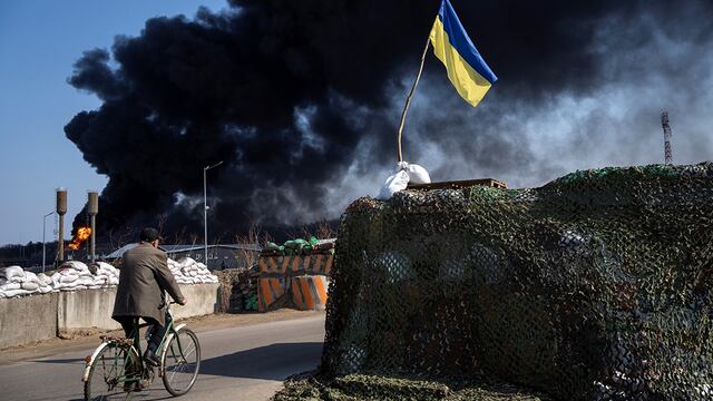 Ucrania. Un hombre anda en bicicleta mientras, de fondo, se levanta una columna de humo negra tras ataques rusos en las afueras de Kiev. (AP / Rodrigo Abd)