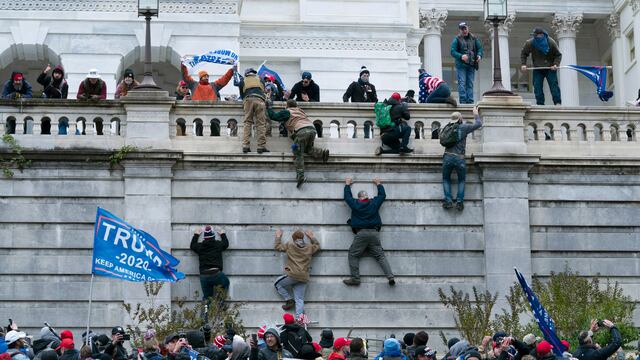 Simpatizantes de Donald Trump escalan un muro del Capitolio.