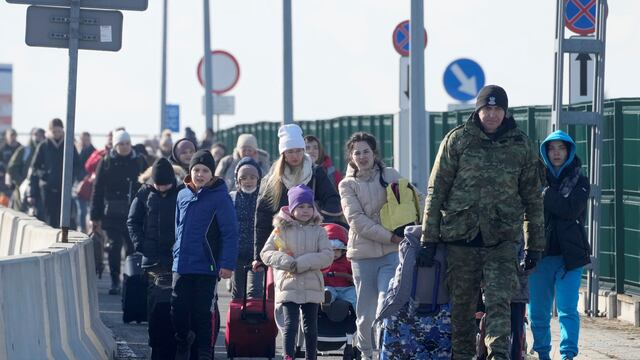 Cruce de Korczowa. Un guardia fronterizo polaco ayuda a los refugiados de Ucrania a llegar a Polonia (AP).