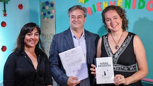 La psicóloga social Miriam Morales sostiene en sus manos su libro "Niñas Sirvientas", mientras el presidente del Concejo Deliberante, Gastón Millón, muestra la declaración "de interés cultural" otorgada a la obra.