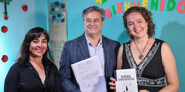La psicóloga social Miriam Morales sostiene en sus manos su libro "Niñas Sirvientas", mientras el presidente del Concejo Deliberante, Gastón Millón, muestra la declaración "de interés cultural" otorgada a la obra.