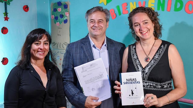 La psicóloga social Miriam Morales sostiene en sus manos su libro "Niñas Sirvientas", mientras el presidente del Concejo Deliberante, Gastón Millón, muestra la declaración "de interés cultural" otorgada a la obra.