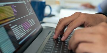 Hands of programmer writing code on laptop