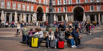 En esta imagen de archivo, turistas esperan sentados con sus maletas en un banco de la Plaza Mayor, en el centro de Madrid, el 29 de abril de 2024. (AP Foto/Bernat Armangue, archivo)
