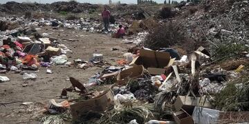 Una madre y sus hijos revolviendo la basura.
