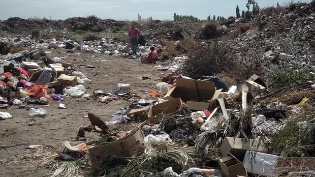 Una madre y sus hijos revolviendo la basura.