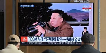 La gente ve una pantalla de noticias de televisión que muestra una imagen del líder de Corea del Norte, Kim Jong Un, presenciando el lanzamiento de prueba reciente de un misil balístico intercontinental.