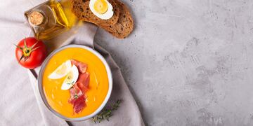 Salmorejo cordobes typical spanish tomato soup similar to the gazpacho, topped with jamon serrano and eggs on gray background, horizontal orientation
