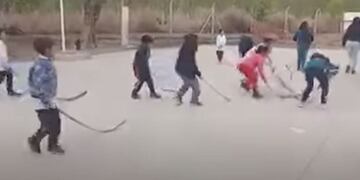 Niños de escuela practican hockey con ramas de palmera, en San Juan.