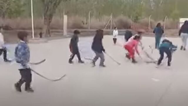 Niños de escuela practican hockey con ramas de palmera, en San Juan.