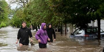 La gente camina por una calle inundada después de la tormenta. (AP)