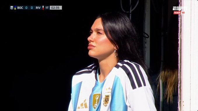 La cantante Dua Lipa ofreció dos conciertos en el Monumental y luego asistió al partido en La Bombonera, donde lució la camiseta argentina. (Captura de TV)