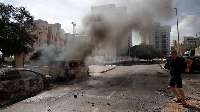Un residente apaga vehículos en llamas en la ciudad israelí de Ashkelon tras el lanzamiento de cohetes desde Gaza, 7 de octubre de 2023. Foto: EFE
