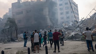 En esta imagen de archivo, reporteros observan mientras palestinos inspeccionan un edificio alcanzado por un bombardeo israelí en la Ciudad de Gaza, 8 de octubre de 2023. El limitado número de periodistas que están en Gaza tratan de informar sobre la guerra con Israel mientras sufren los mismos problemas que la asediada población palestina de la Franja.
