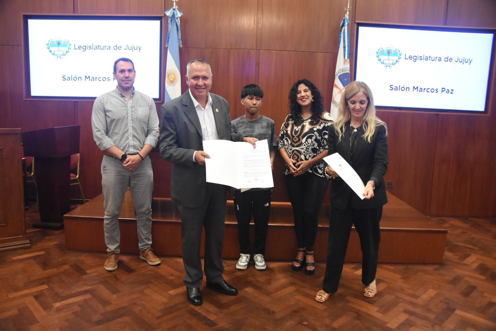 El entrenador Luis Armella exhibe a los presentes en el acto en el salón "Marcos Paz", el reconocimiento que le fue otorgado por la Legislatura.