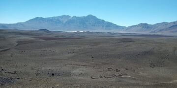Una vista del sitio denominado LD-S25 que incluye estructuras de muros bajos de roca. Al fondo se puede observar la Laguna de Diamante.