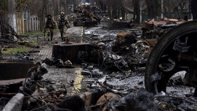 Soldados caminan entre tanques rusos destruidos en Bucha, en las afueras de Kiev. Allí denuncian que se cometieron crímenes de guerra. (AP)