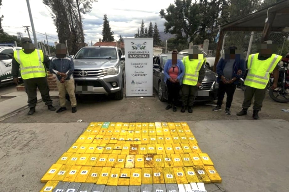 Imagen captada el 18 de noviembre del 2024, en dependencias de la sección "Cafayate" del escuadrón 45 "Salta" de la Gendarmería Nacional. En primer plano los más de cien kilos de cocaína, atrás las tres personas oriundas de Casira (Jujuy) y los vehículos utilizados para la maniobra de narcotráfico.